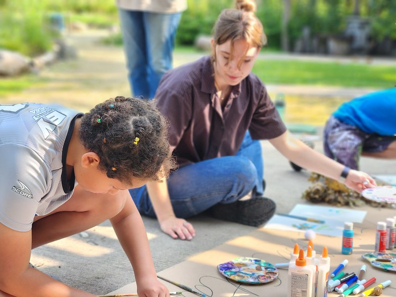 A child participates in an interactive project alongside a guide.