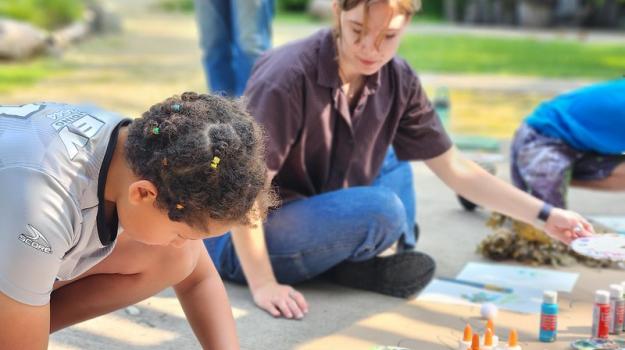 A child participates in an interactive activity alongside an adult guide.